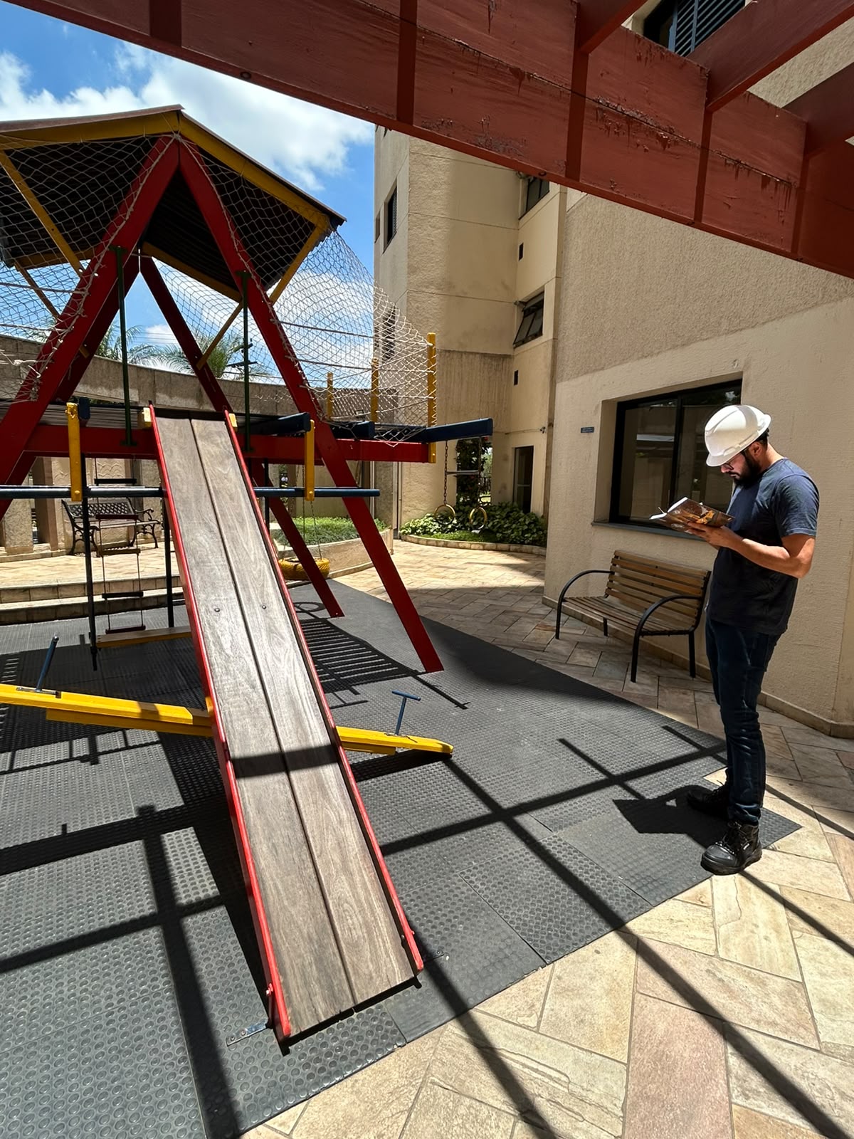 Inspeção presencial de estrutura infantil em playground outdoor, vista de perfil